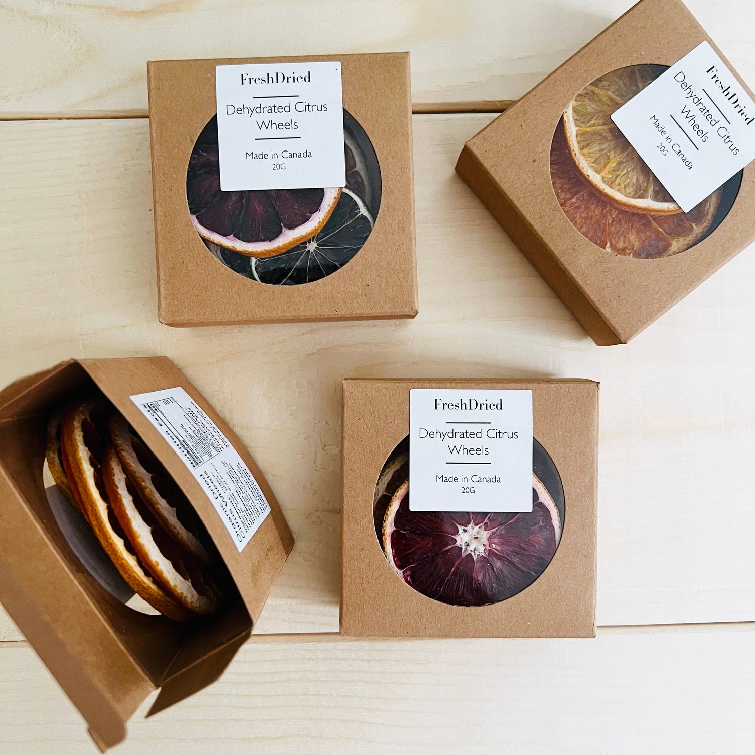 Four boxes of dried citrus wheels with visible brand labels on a wooden surface.