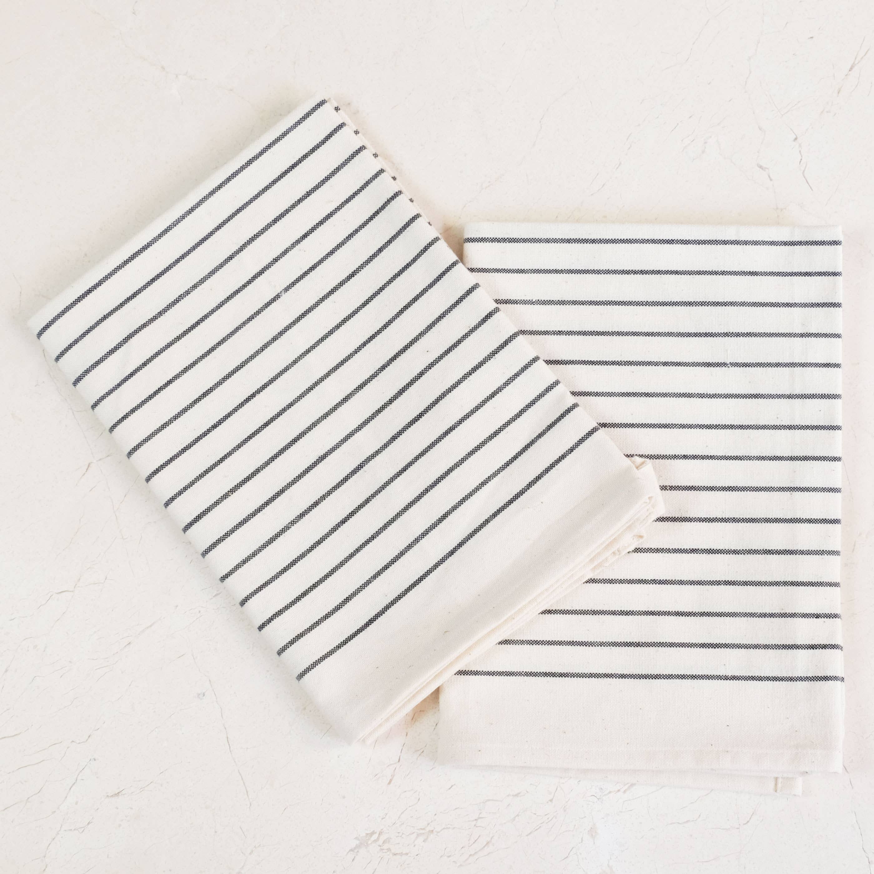 Two striped towels, one folded and one unfolded, on a light background