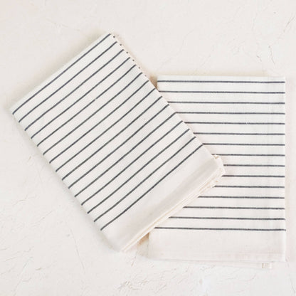 Two striped towels, one folded and one unfolded, on a light background