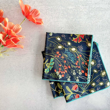 Two floral-patterned napkins on a light gray surface with orange flowers.