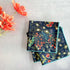 Two floral-patterned napkins on a light gray surface with orange flowers.
