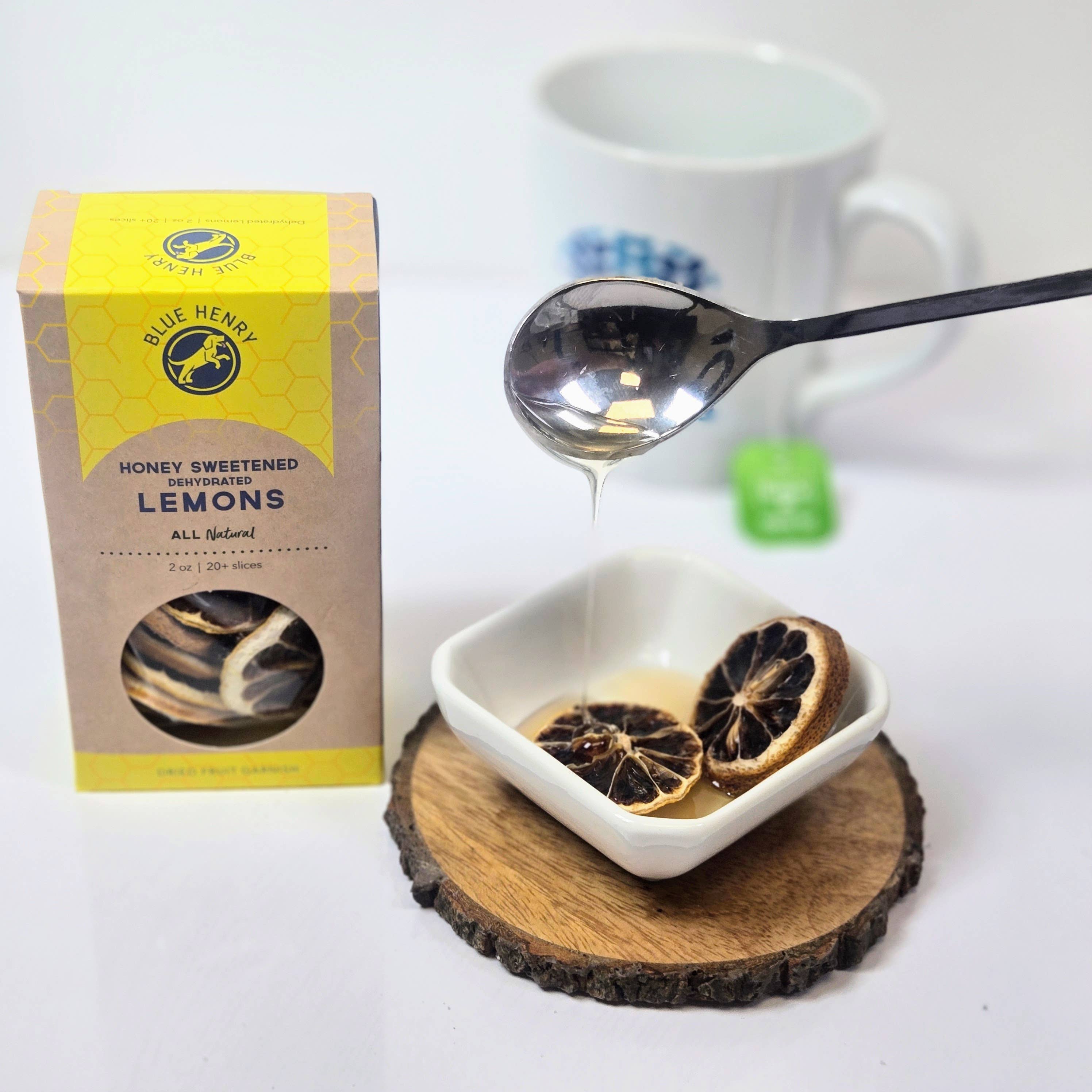 Dried lemons in a bowl with a spoon and box of Blue Herb Honey Sweetened Lemons on a white background