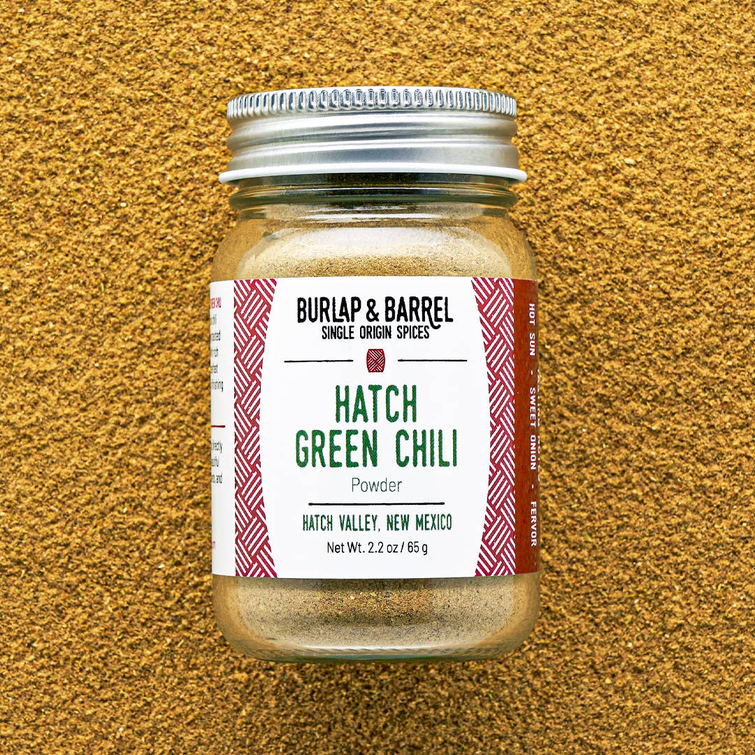 Jar of Burlap &amp; Barrel Hatch Green Chili Powder on a textured brown background