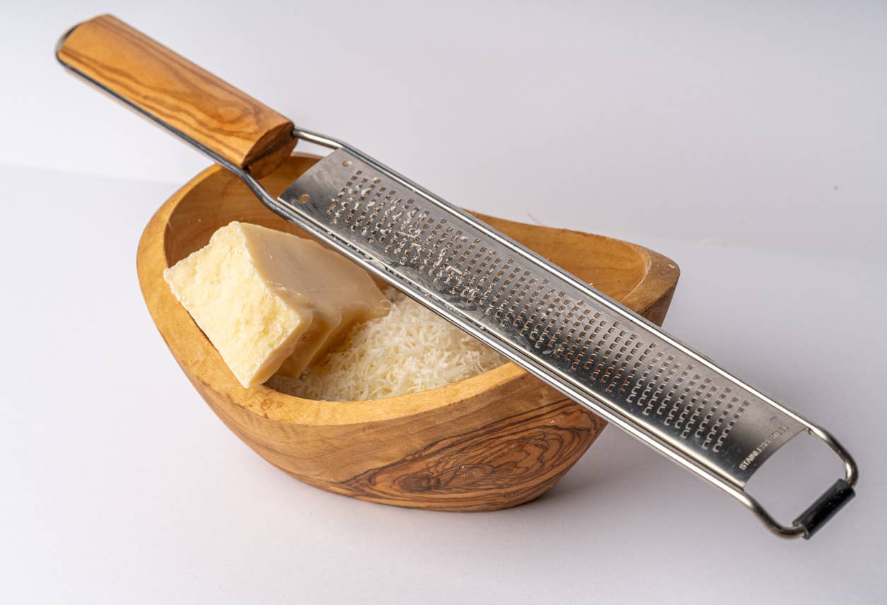 Close up of a fine Italian Mandolin Paddle Grater sitting on a bowl of grated cheese
