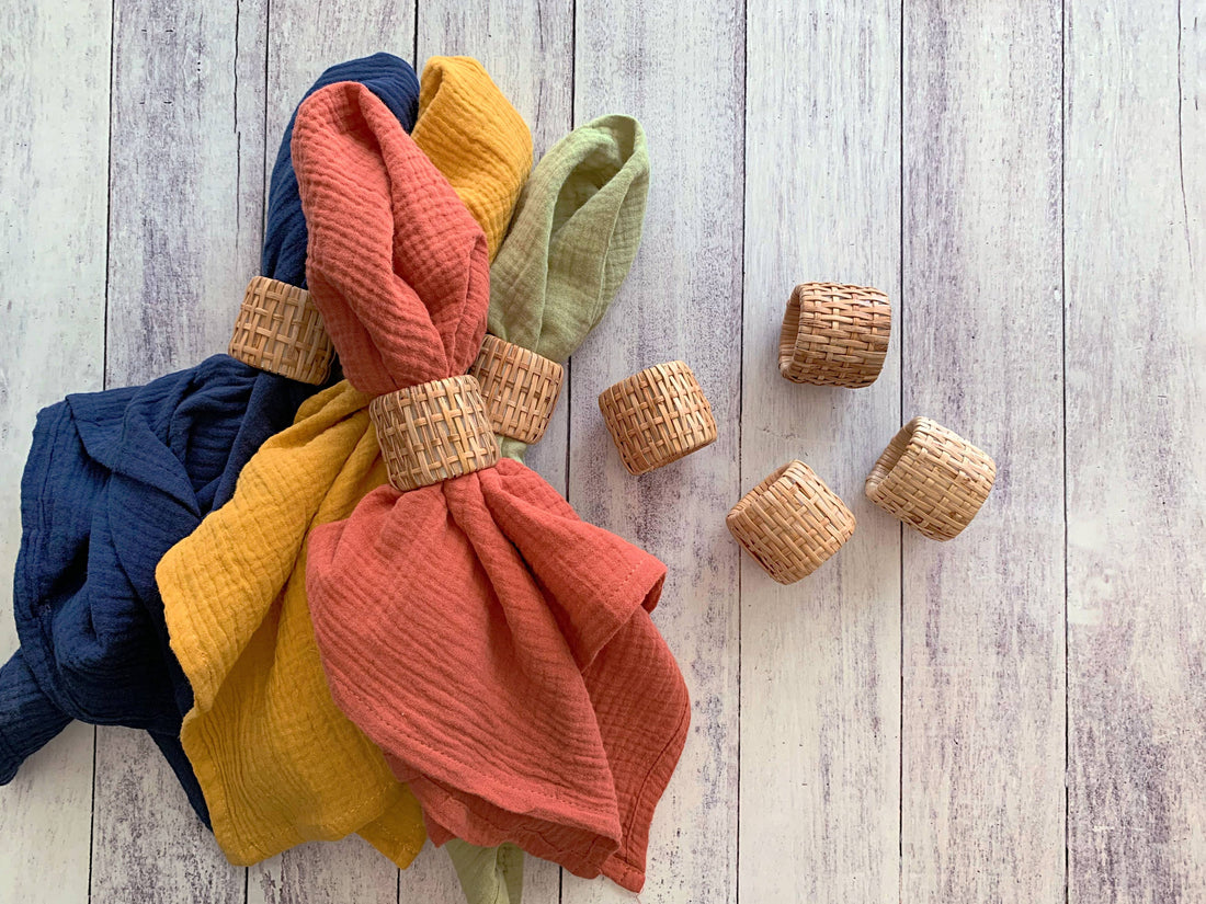 Colorful textured napkins with rattan napkin rings on a wooden surface