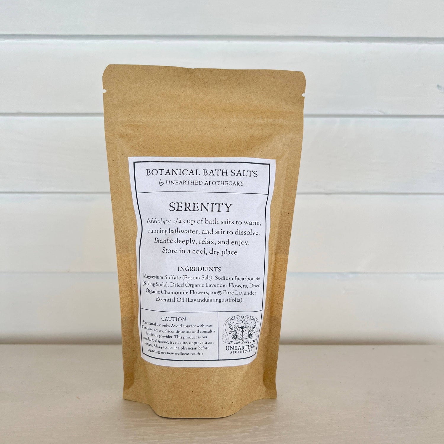 Kraft paper packaging of Botanical Bath Salts with a label on a light wooden surface.