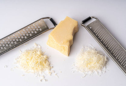 Block of cheese with coarse and fine Italian Mandolin Paddle Graters and grated cheese