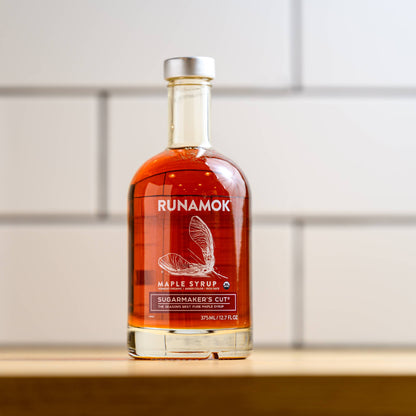 Bottle of Runamok maple syrup on a wooden surface with a white tiled wall background