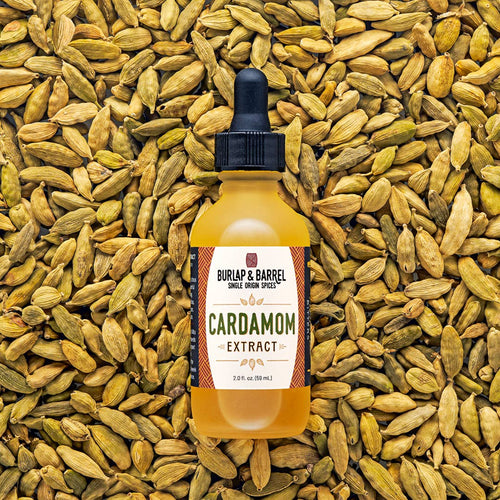 Bottle of Burlap & Barrel Cardamom Extract surrounded by cardamom seeds