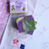 Purple and green soap bars with packaging on a textured surface