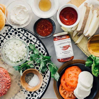 Assorted ingredients for making burgers on a table with a jar of sauce.