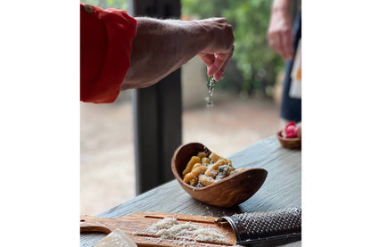 Person seasoning pasta in an Italian Olivewood Serving Bowl 