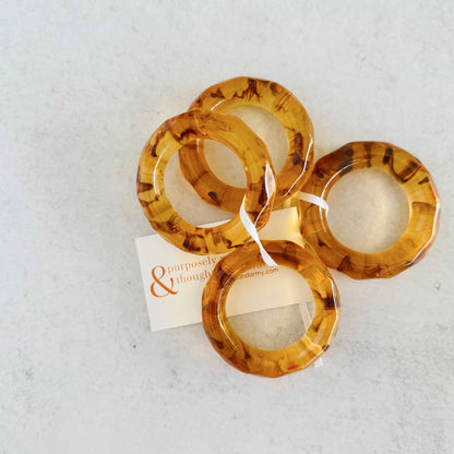 Set of tortoiseshell bangles on a textured white surface with a brand card.