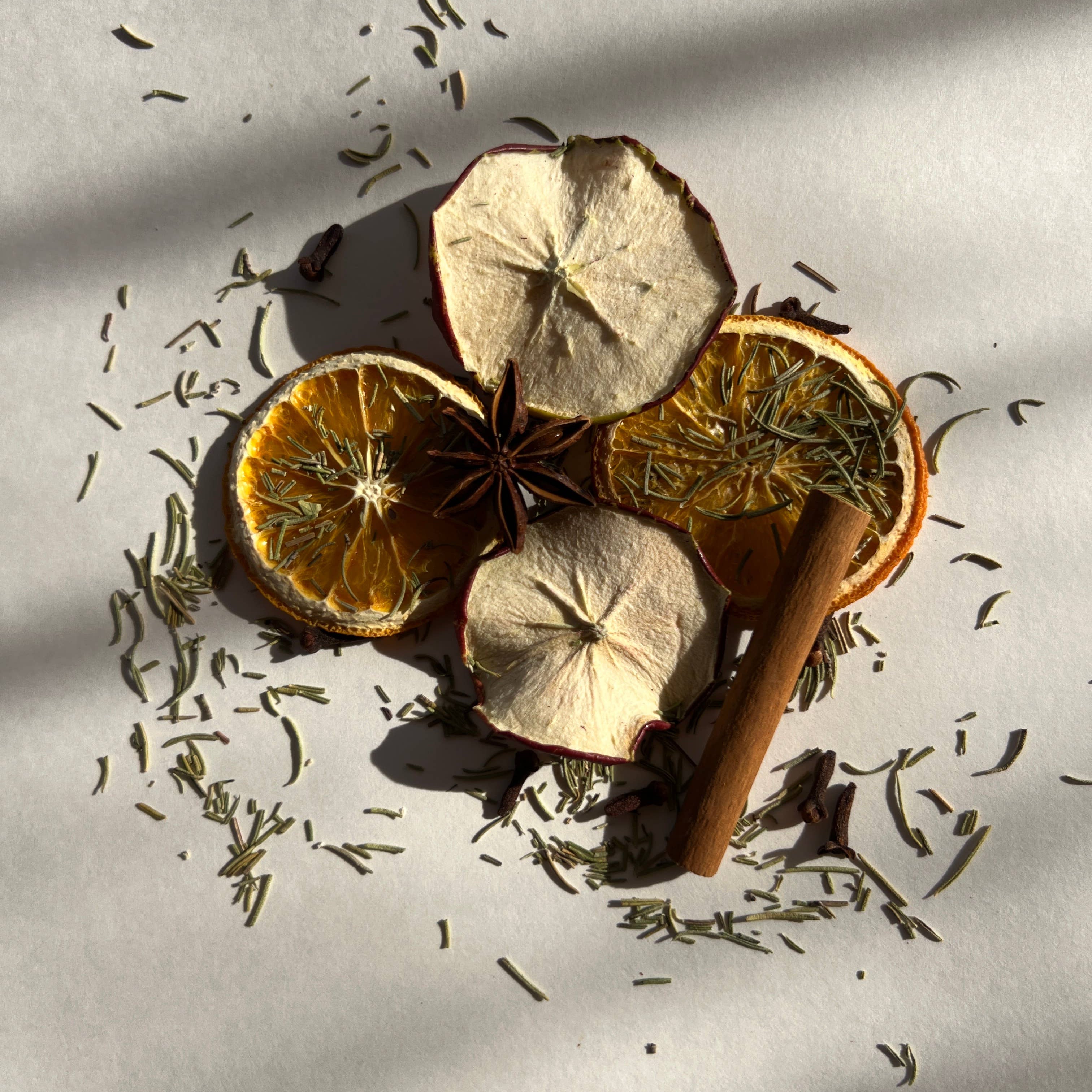 Spices including cinnamon sticks, star anise, and orange slices on a light background