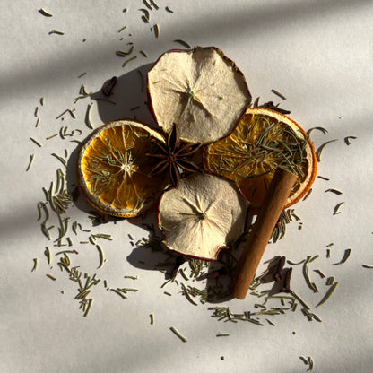 Spices including cinnamon sticks, star anise, and orange slices on a light background