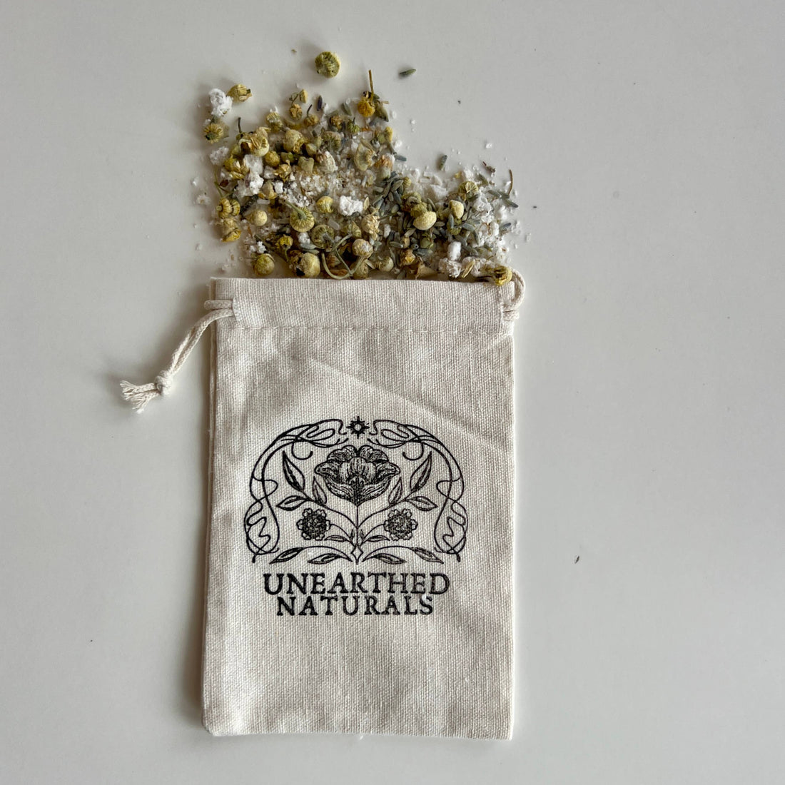 Mud pack with herbs spilling out of a bag labeled &