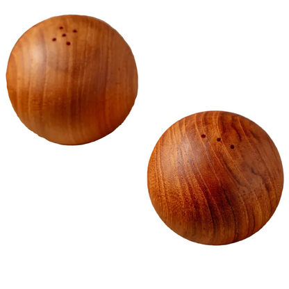 Two round teak wood salt and pepper shakers with visible wood grain and small holes on top, shown on a plain white background.