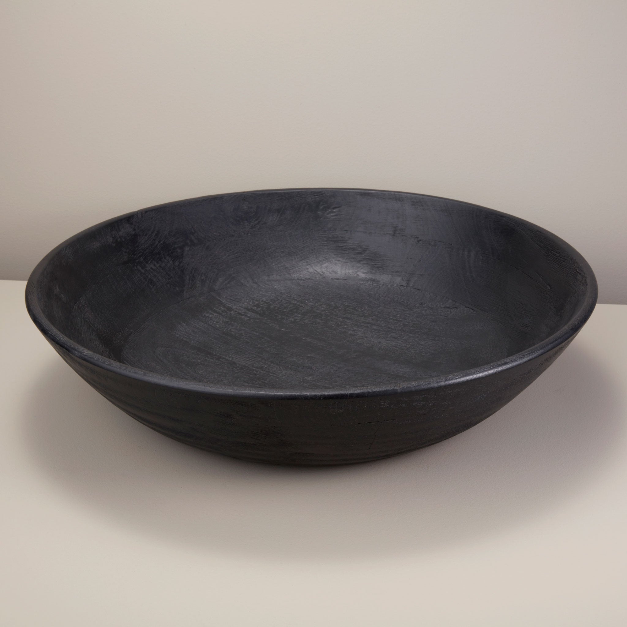 Arendal black mango wood bowl on a white surface with a plain background