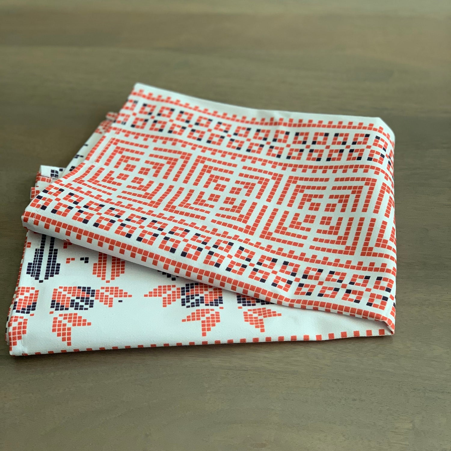 Two patterned fabric swatches stacked on a wooden surface