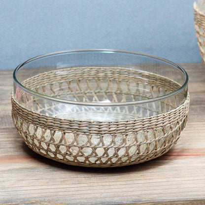 Glass bowl with woven seagrass rim on a wooden surface