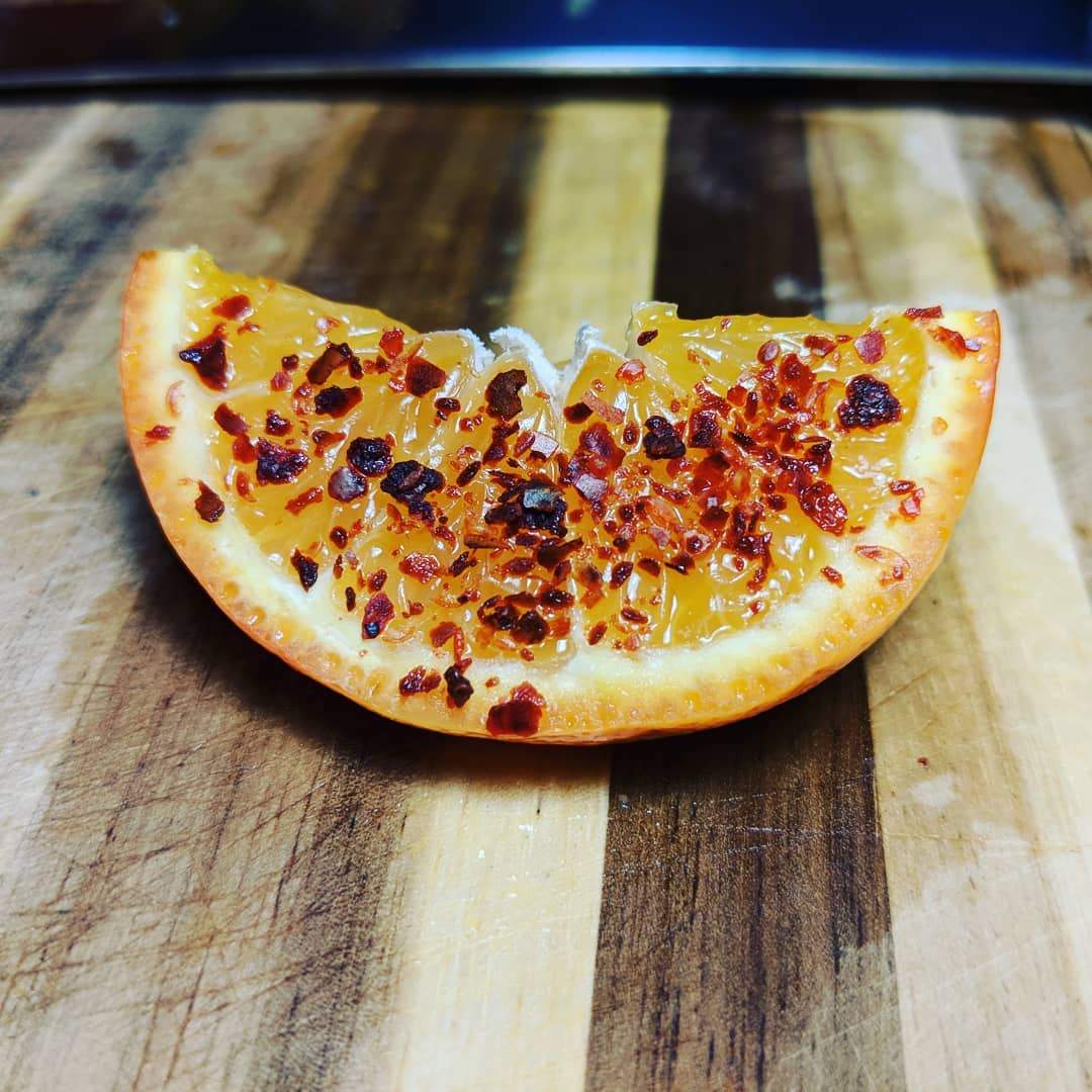 Sliced fruit with a sprinkle of silk chili (aleppo) on a wooden cutting board