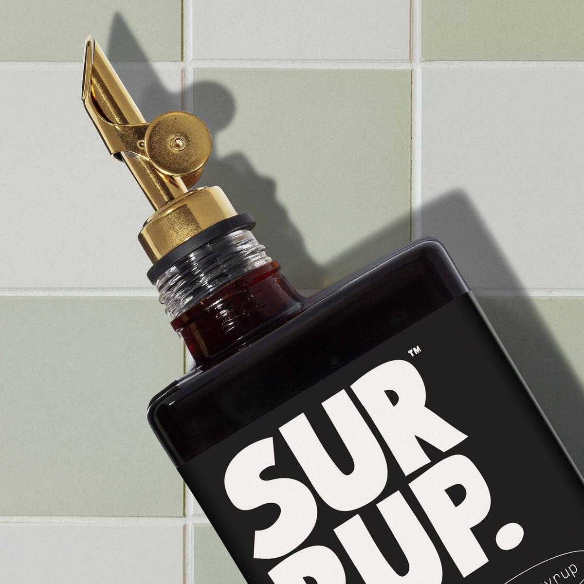 Bottle of Sur Dup with gold cap on a tiled wall background