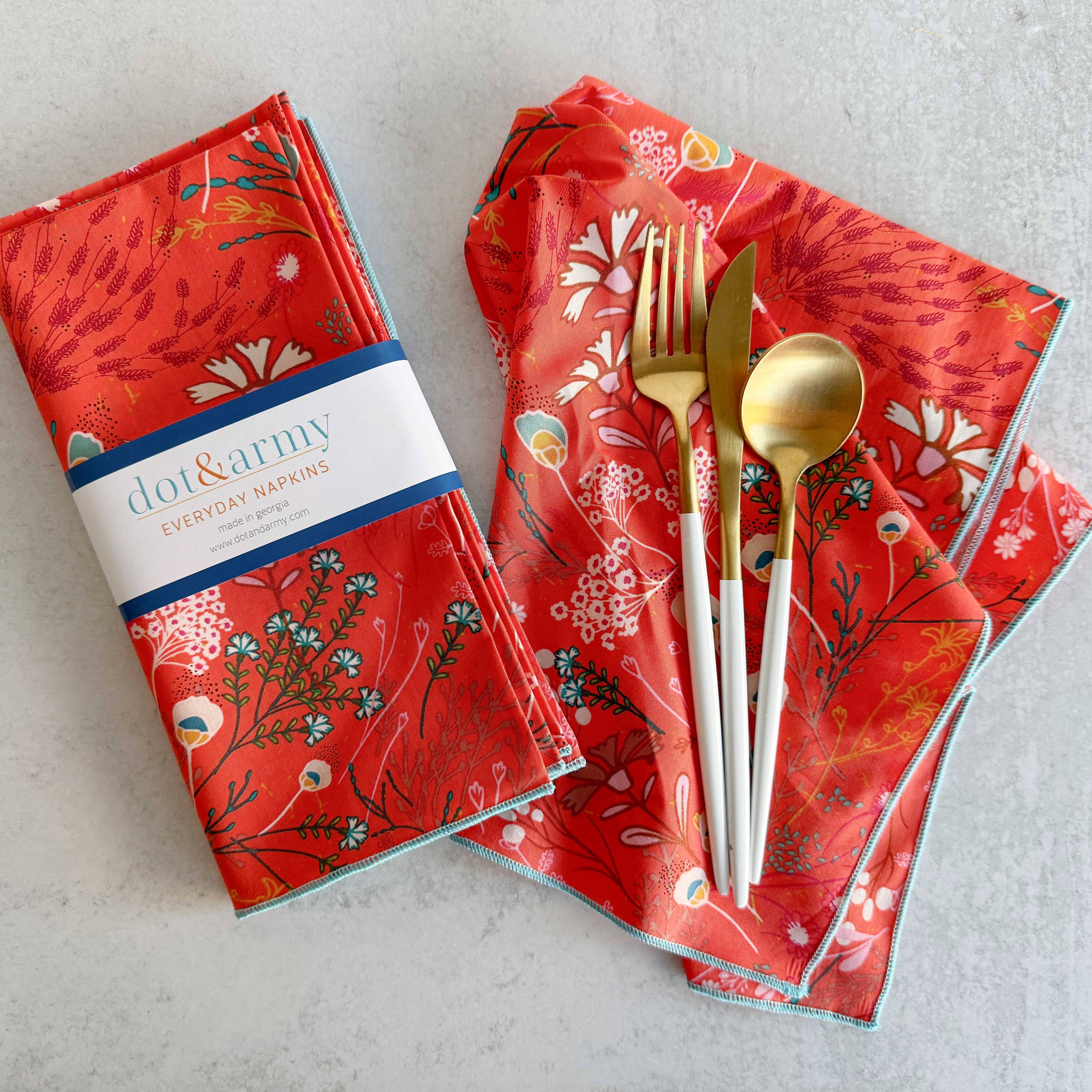 Red patterned napkins with gold cutlery on a light gray surface