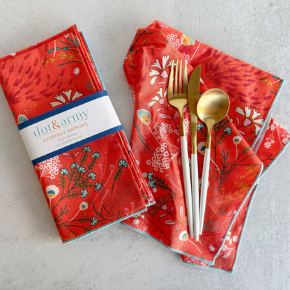Red patterned napkins with gold cutlery on a light gray surface