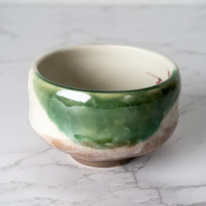 Ceramic bowl with green and beige glaze on a marble surface