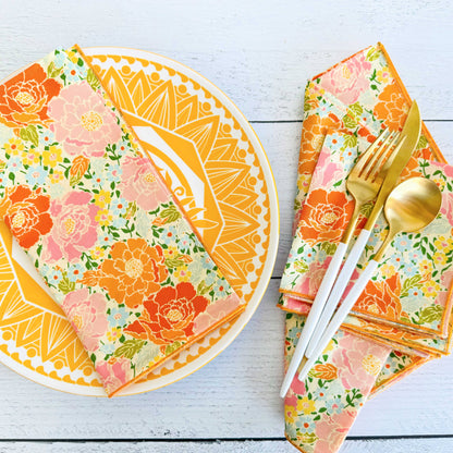 Floral-patterned plates, napkins, and cutlery on a white wooden surface