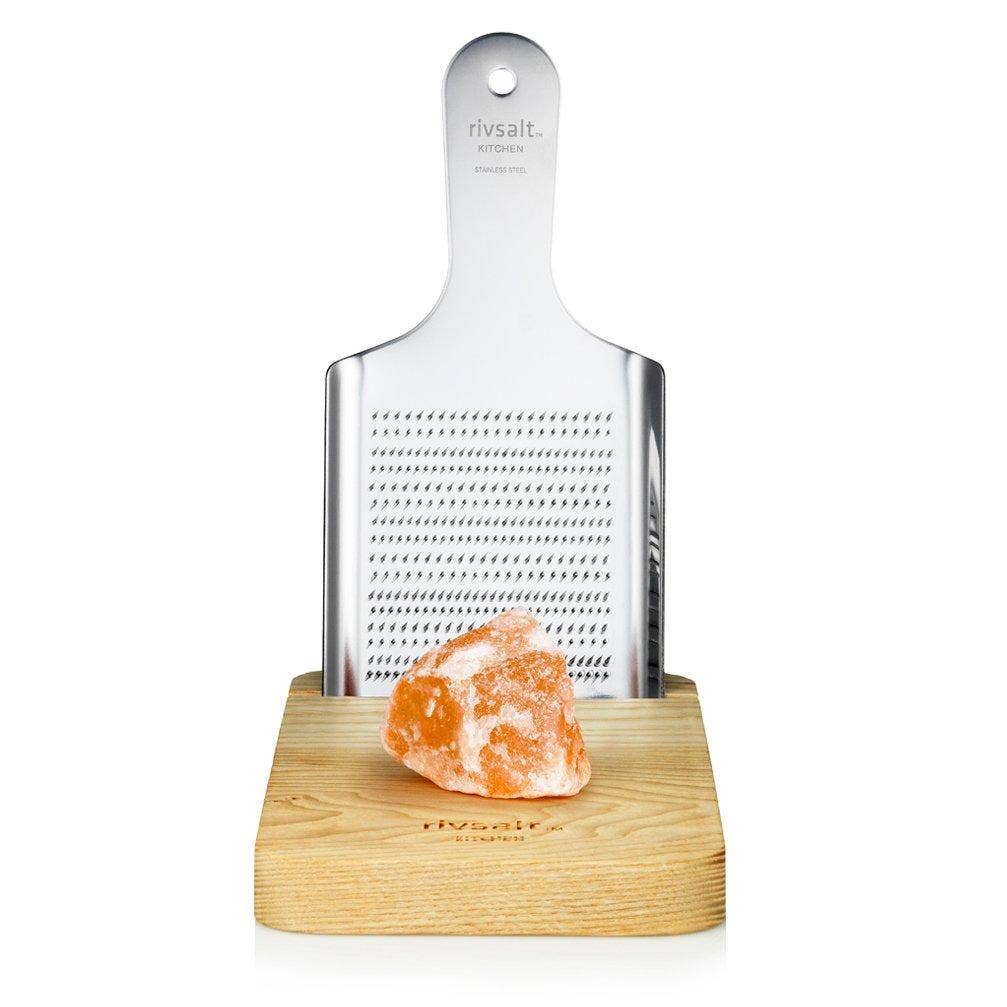 A rivsalt salt grater with a wooden base and a salt crystal on a white background