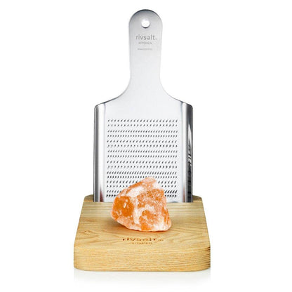 A rivsalt salt grater with a wooden base and a salt crystal on a white background