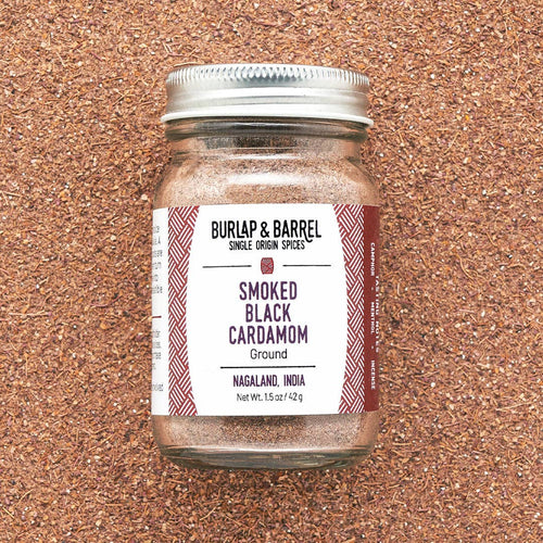 Jar of Burlap & Barrel Smoked Black Cardamom on a cork background