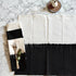 Black and white placemat with a napkin featuring cutlery and eucalyptus on a marble surface.
