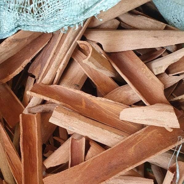 Stack of cinnamon with a green mesh bag in the background