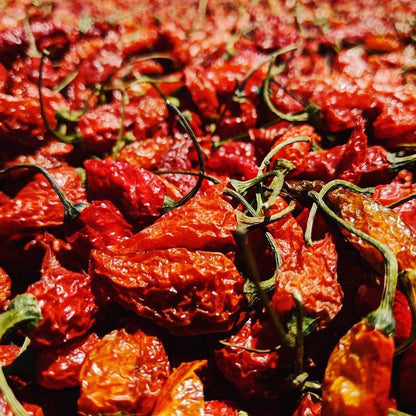 Close-up of dried red chili peppers with green stems.