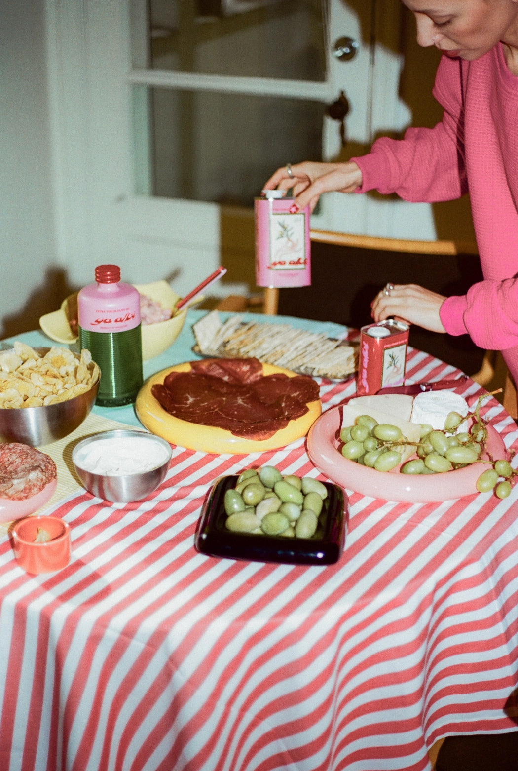 Person preparing food at a table with a striped tablecloth, featuring Ya Albi olive oil