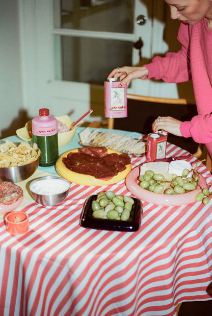 Person preparing food at a table with a striped tablecloth, featuring Ya Albi olive oil
