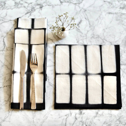 Folded black and white place mat with cutlery on a marble surface