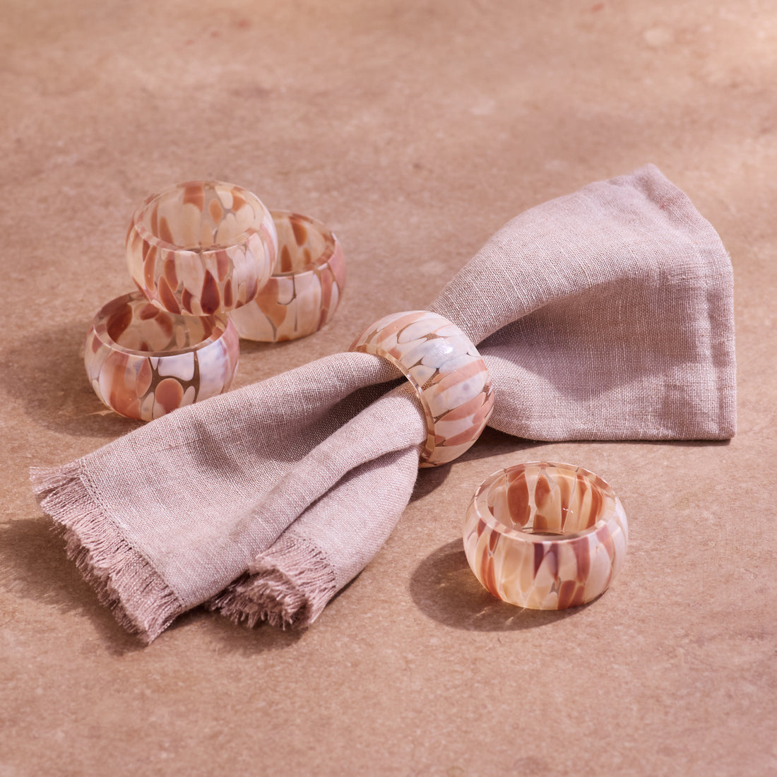 Set of marbled patterned glass napkin rings on a beige background