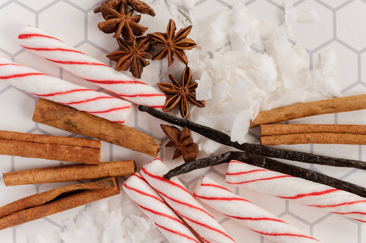 Cinnamon sticks, star anise, vanilla beans, and candy canes on a white surface with a hexagonal pattern.