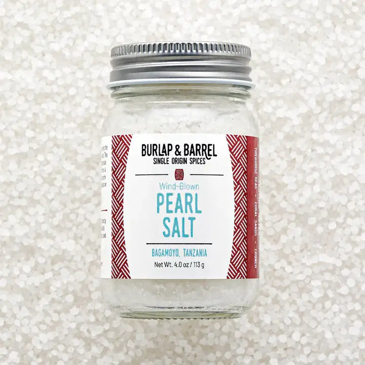 Jar of pearl salt with a Burlap &amp; Barrel label on a textured white background