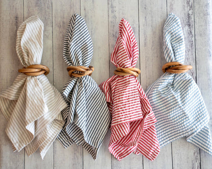 Four folded napkins with wooden bangles napkin rings on a wooden surface