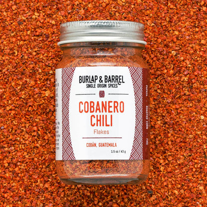 Jar of Burlap &amp; Barrel Cobanero Chili Flakes on a textured red background