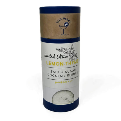 A cylindrical product package for Blue Henry Lemon-Thyme Salt + Sugar Cocktail Rimmer, featuring a kraft paper top band with a blue logo, a white middle label with blue and yellow text, and a dark blue bottom section with a small clear window showing the salt inside.
