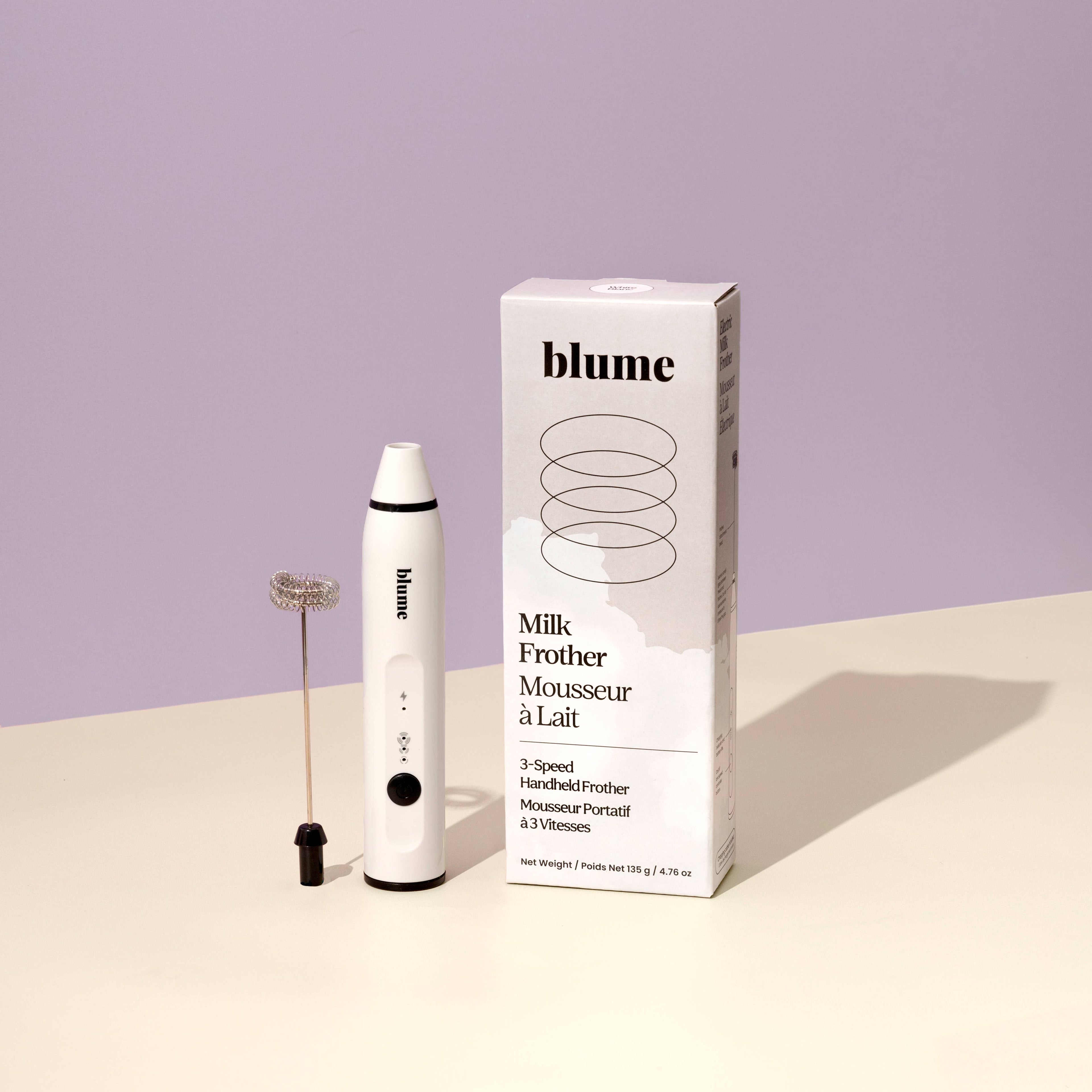 Blume Milk Frother with packaging on a light purple background