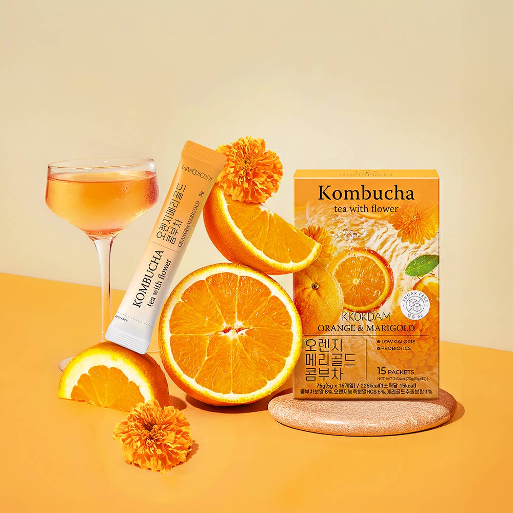 Kombucha tea with orange slices and a glass on a yellow background