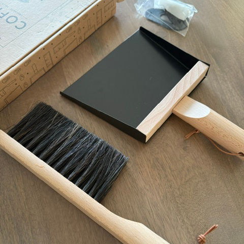 Cleaning brush and dustpan on a wooden floor