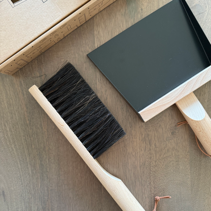 Cleaning brush and black rectangular object on a wooden surface