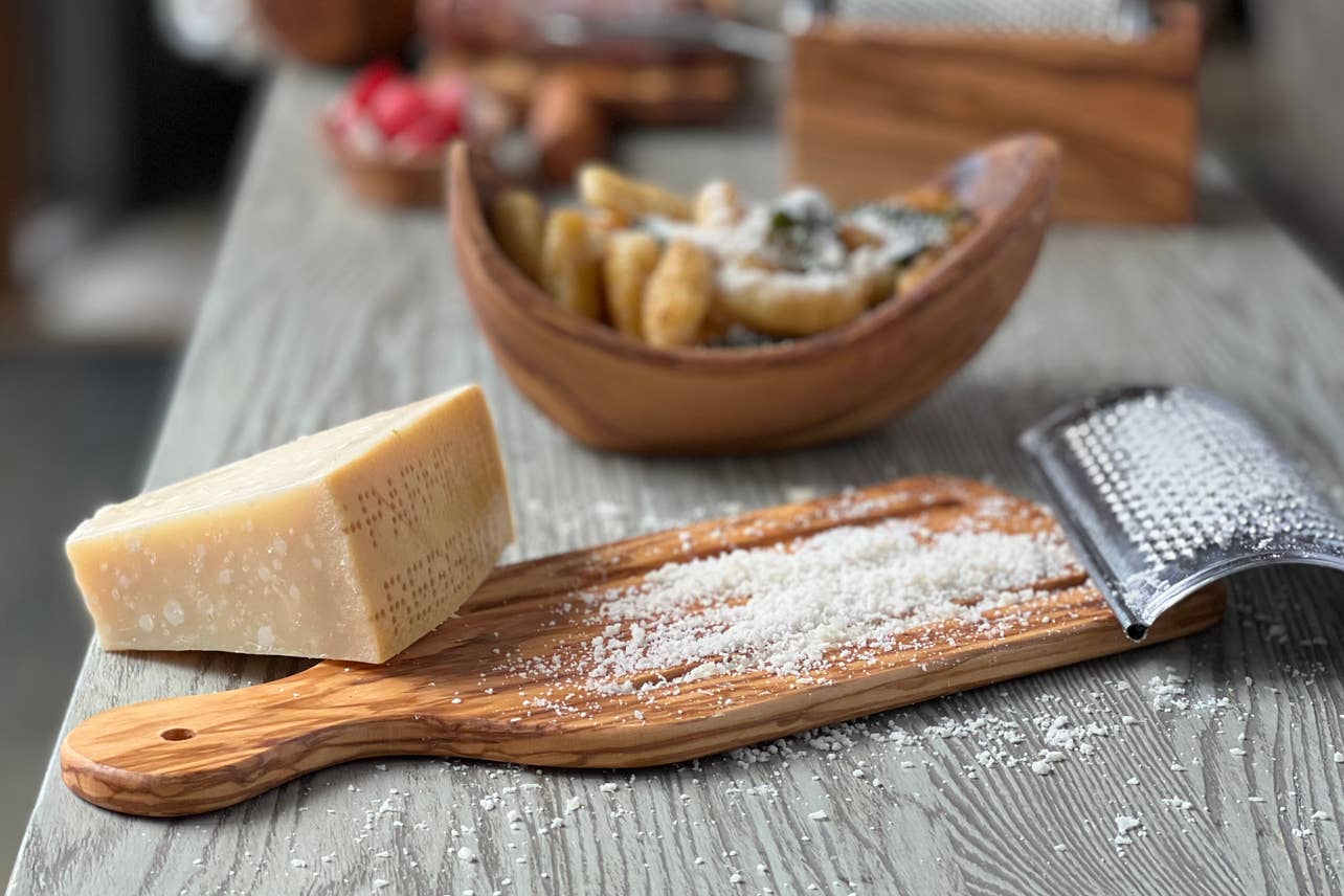 Block of Parmesan cheese on a wooden board with a grater